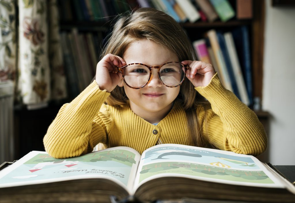 Menina adorável a com óculos a ler. Atividades de tempos livres. Quadro Mágico em Aveiro. Centro de estudos.